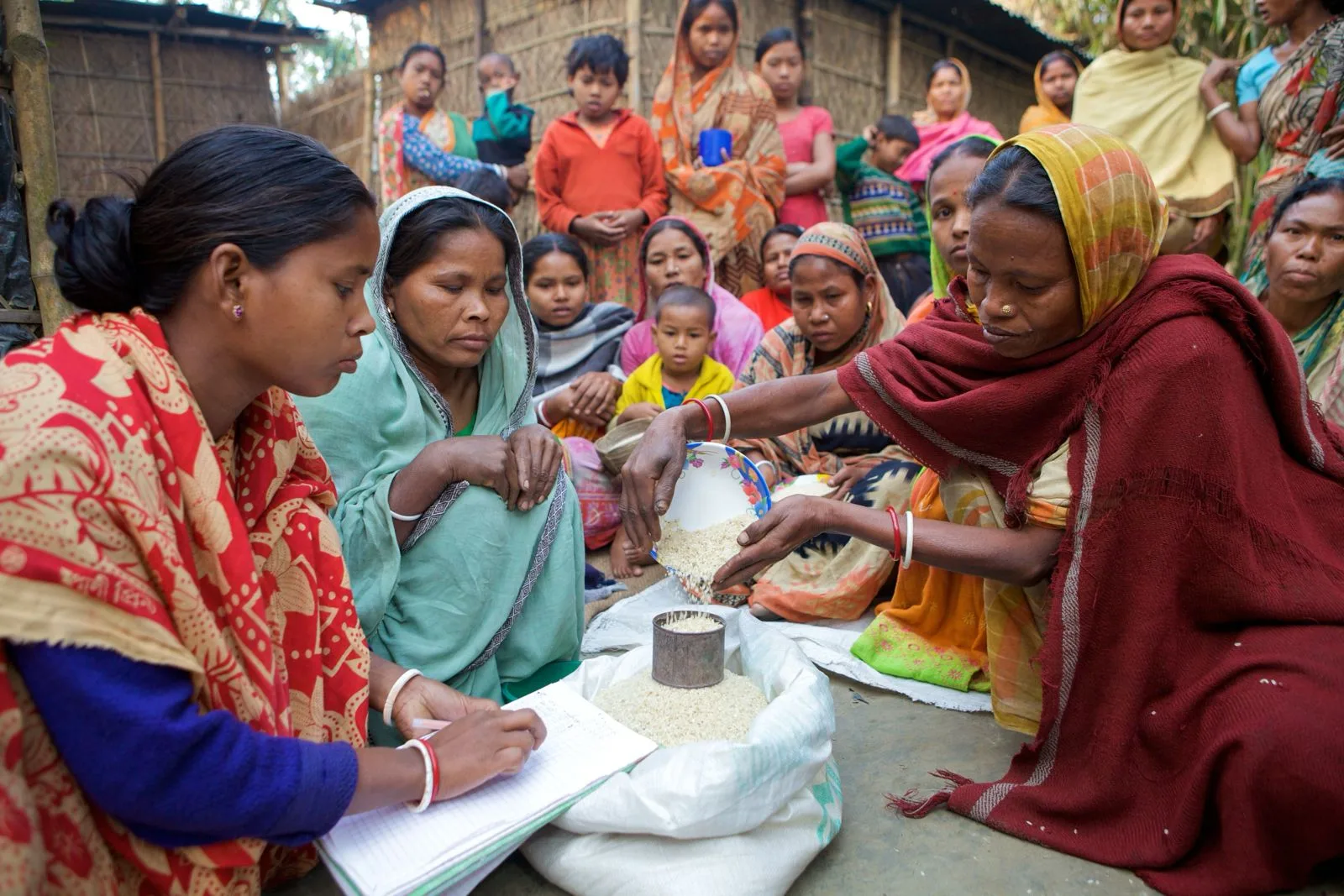 Women recording contributions at a community savings group meeting